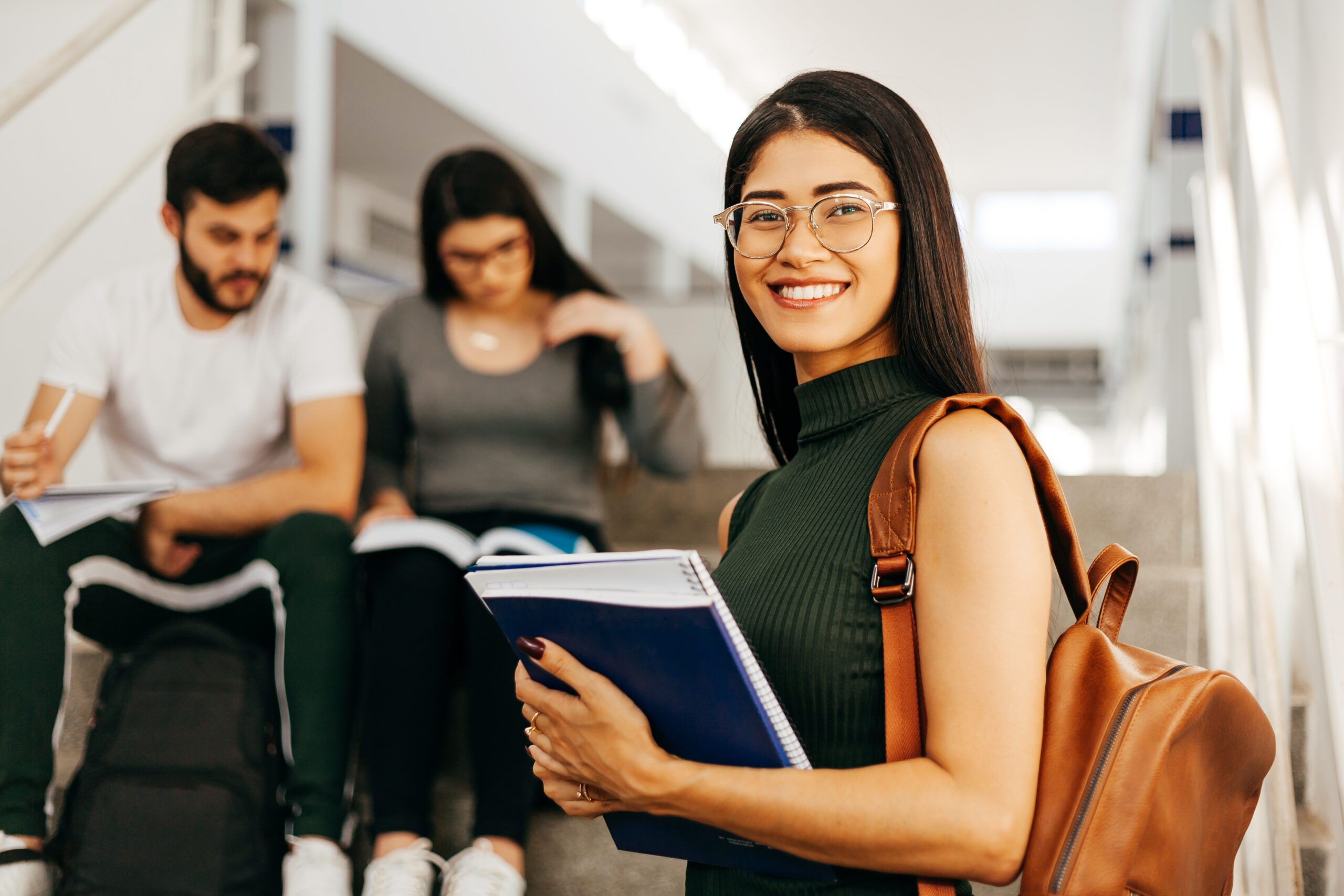 Portrait of young Brazilian student with backpack carrying books in college.